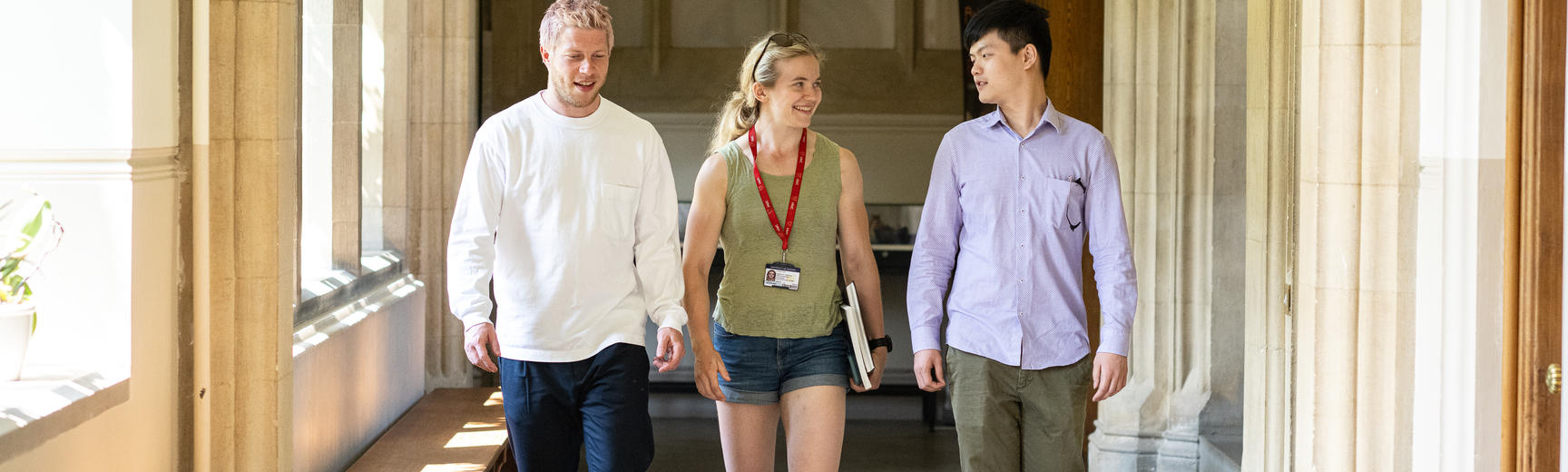 Two men and a woman walking down corridor