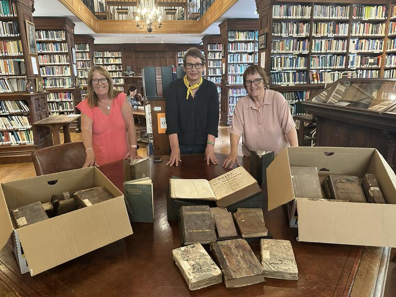 Kate Alderson-Smith, Nans Davies and Mair Potter in the college library with a collection of books