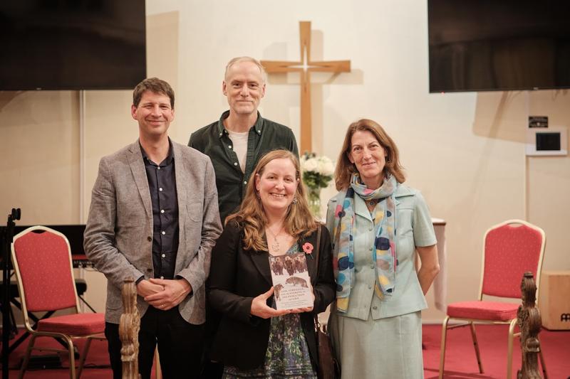 Two men and two women pose with one woman holding a book in her hand