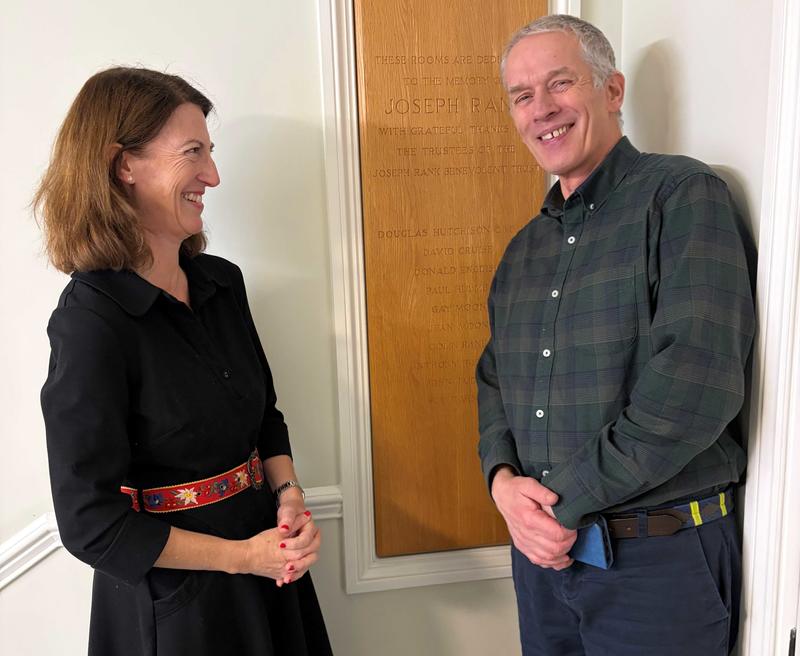 A woman and a man stand next to an engraved wooden panel