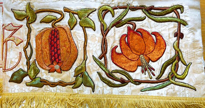 Detail of an embroidered cloth with a piece of fruit and flower 