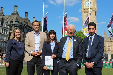 Five people in front of Big Ben with person in centre holding a report