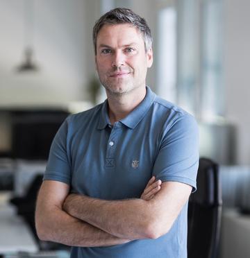 A man in a T-shirt standing with folded arms