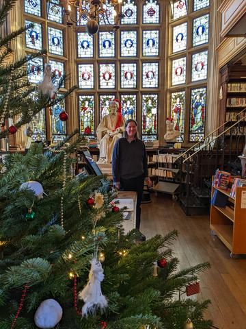 A photograph with a Christmas tree in the foreground, then a staff member, followed by the stained glass windows.