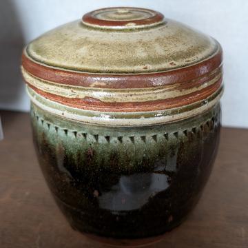 A ginger pot with lid and green glaze on the body.  Around the rim there is a small triangular pattern. 