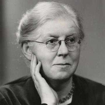 A portrait in black and white of a women with white hair, smiling looking away from the camera.