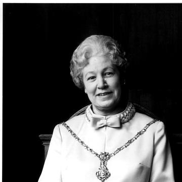 Black and white photograph of a female.  Figure seated in a chair. 