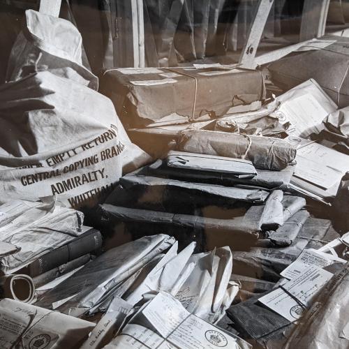 Black and white photograph of piles of parcels and bags containing letters all crowded together