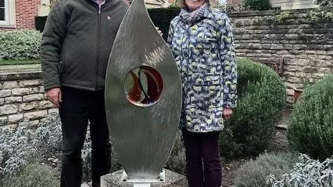 A man and a woman visiting the sculpture, 'Kindle', in the College quad. 