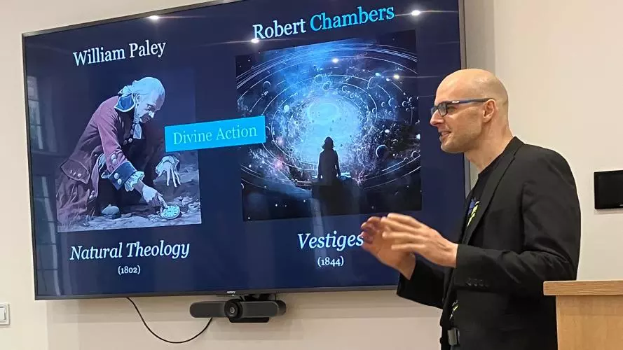 A student speaks in front of a screen depicting William Paley and Robert Chambers