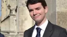Photograph of Nicholas Stone in Radcliffe Square wearing a suit and tie and smiling at the camera. 