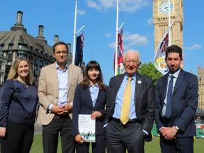 Five people in front of Big Ben with person in centre holding a report