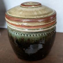 A ginger pot with lid and green glaze on the body.  Around the rim there is a small triangular pattern. 