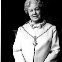 Black and white photograph of a female.  Figure seated in a chair. 