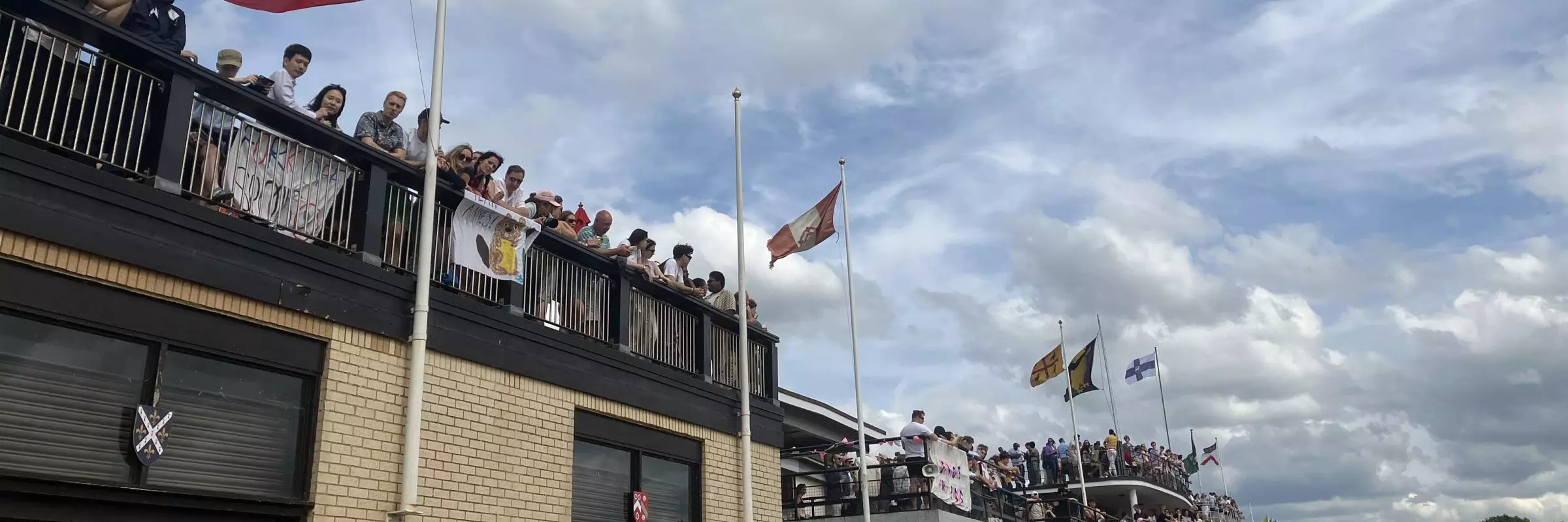 Fans on balcony with college flags flying in the background